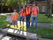 Volunteers in orange vests standing next to a storm drain